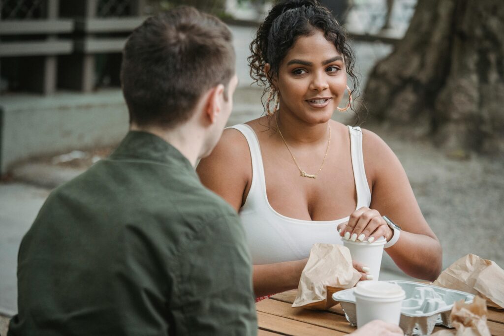 A young couple enjoying a coffee date at an outdoor café, engaging in lively conversation.
